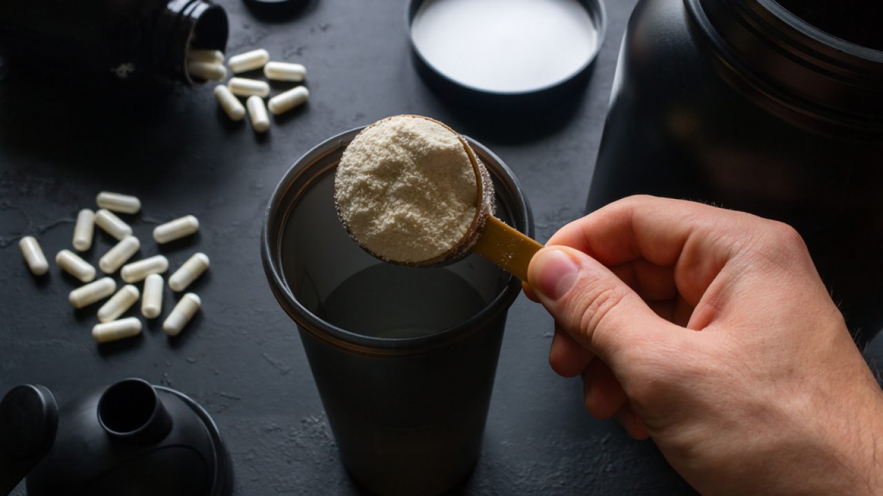 mão adicionando whey protein no copo